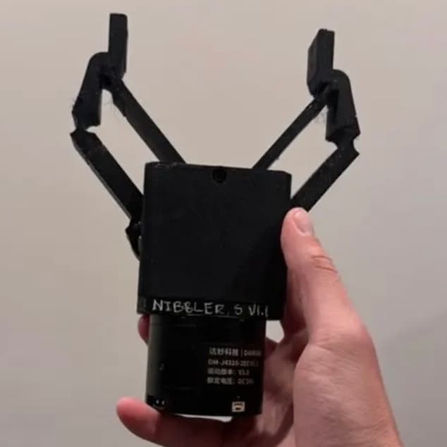 Small Nibbler v1.0 two-jaw gripper held in hand, jaws open.